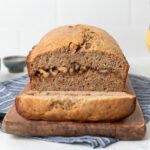 Banana bread loaf with a slice cut off revealing the inside swirl of cinnamon and walnuts,