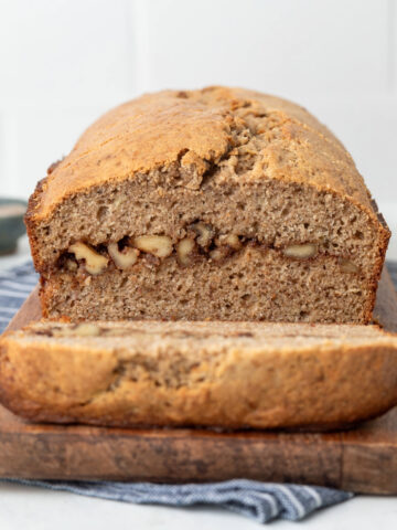 Banana bread loaf with a slice cut off revealing the inside swirl of cinnamon and walnuts,
