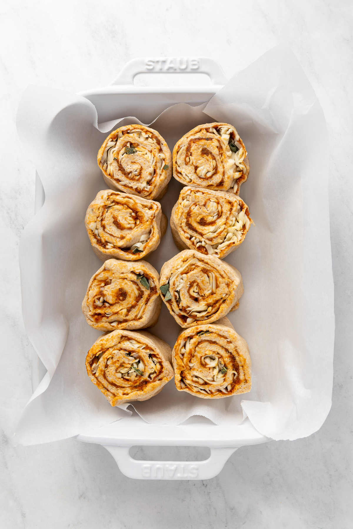 Unbaked butternut squash rolls in a baking dish.