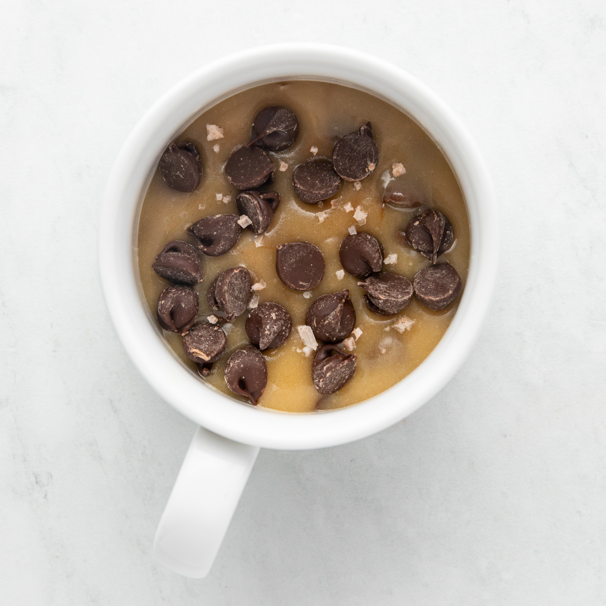 Unbaked cookie dough batter in a white mug.