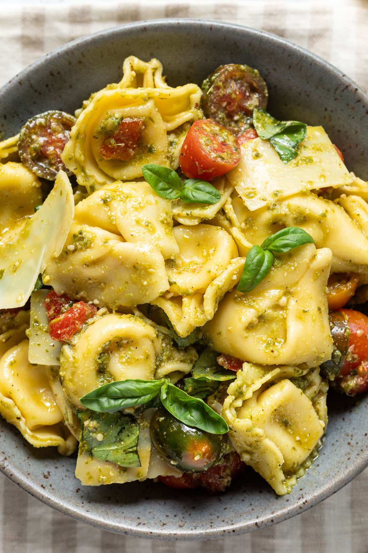 Close up of pesto tortellini salad in a gray bowl.