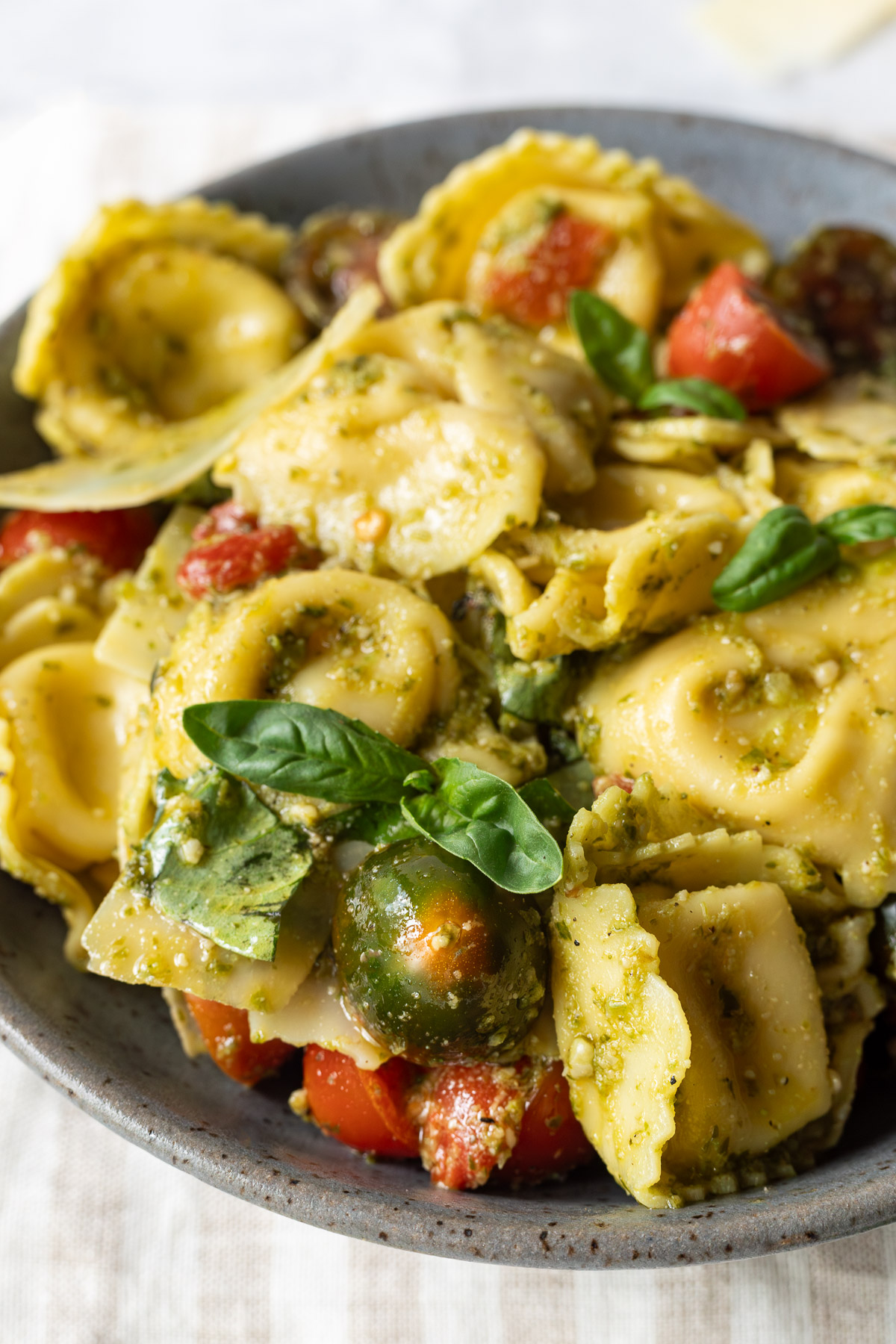 Close up side angle of pesto tortellini salad in a gray bowl.