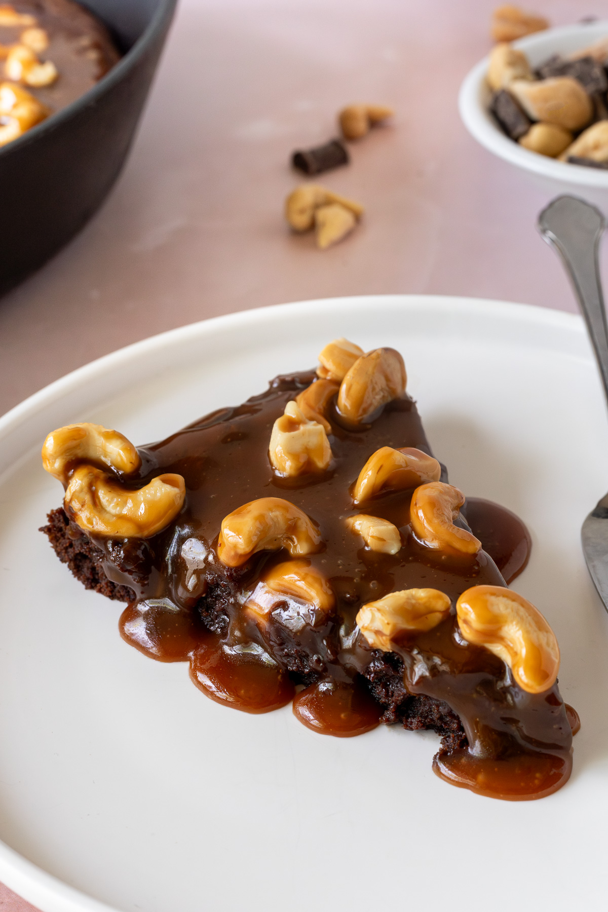 A slice of brownie topped with cashew caramel on a white plate.