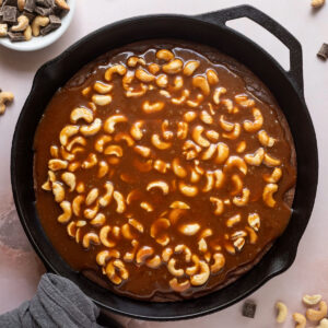Brownie baked in a cast iron skillet topped with cashew caramel.