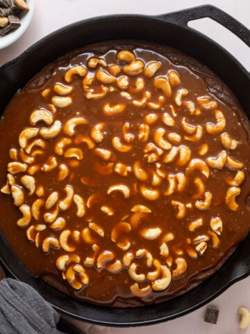 Brownie baked in a cast iron skillet topped with cashew caramel.