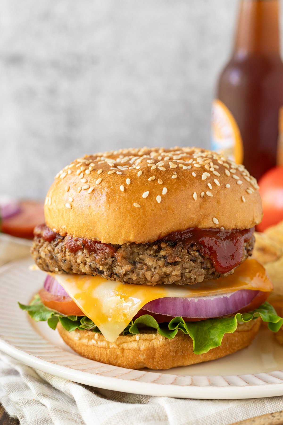 Close up image of a walnut burger on a bun topped with ketchup, cheese, red onion, and lettuce.