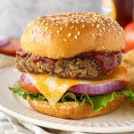 Close up image of a walnut burger on a bun topped with ketchup, cheese, red onion, and lettuce.