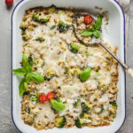 A spoon sticking out of a casserole dish full of broccoli quinoa casserole.