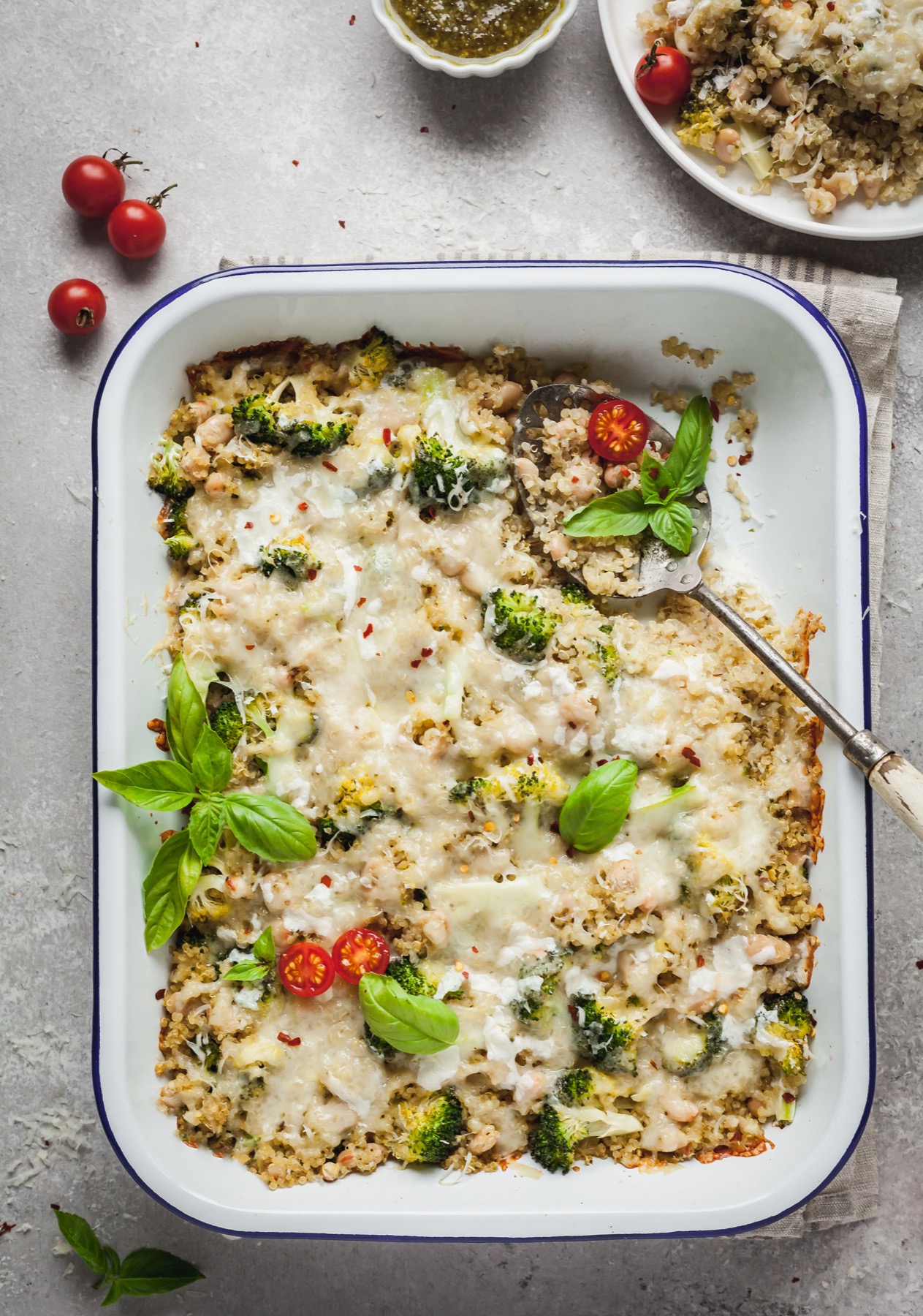 A spoon sticking out of a casserole dish full of broccoli quinoa casserole. 