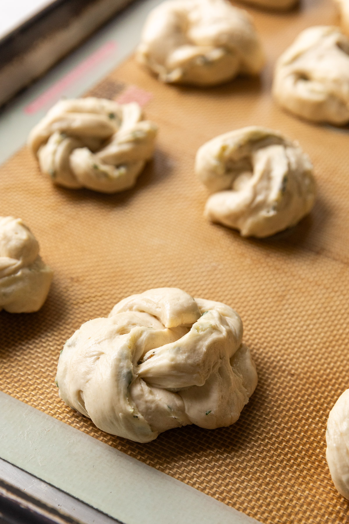 Unbaked garlic knots on a sheet tray.