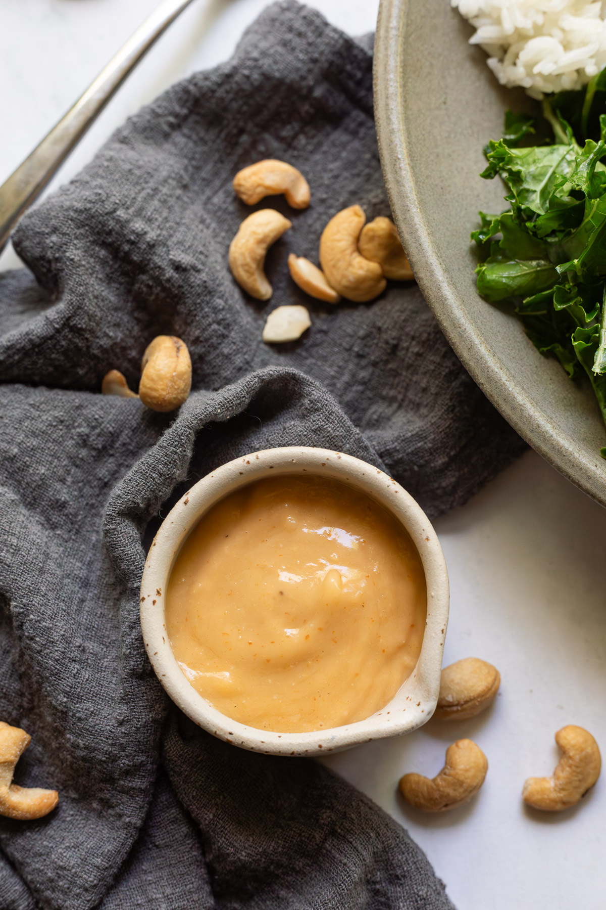 Creamy cashew dressing in a small pouring cup.