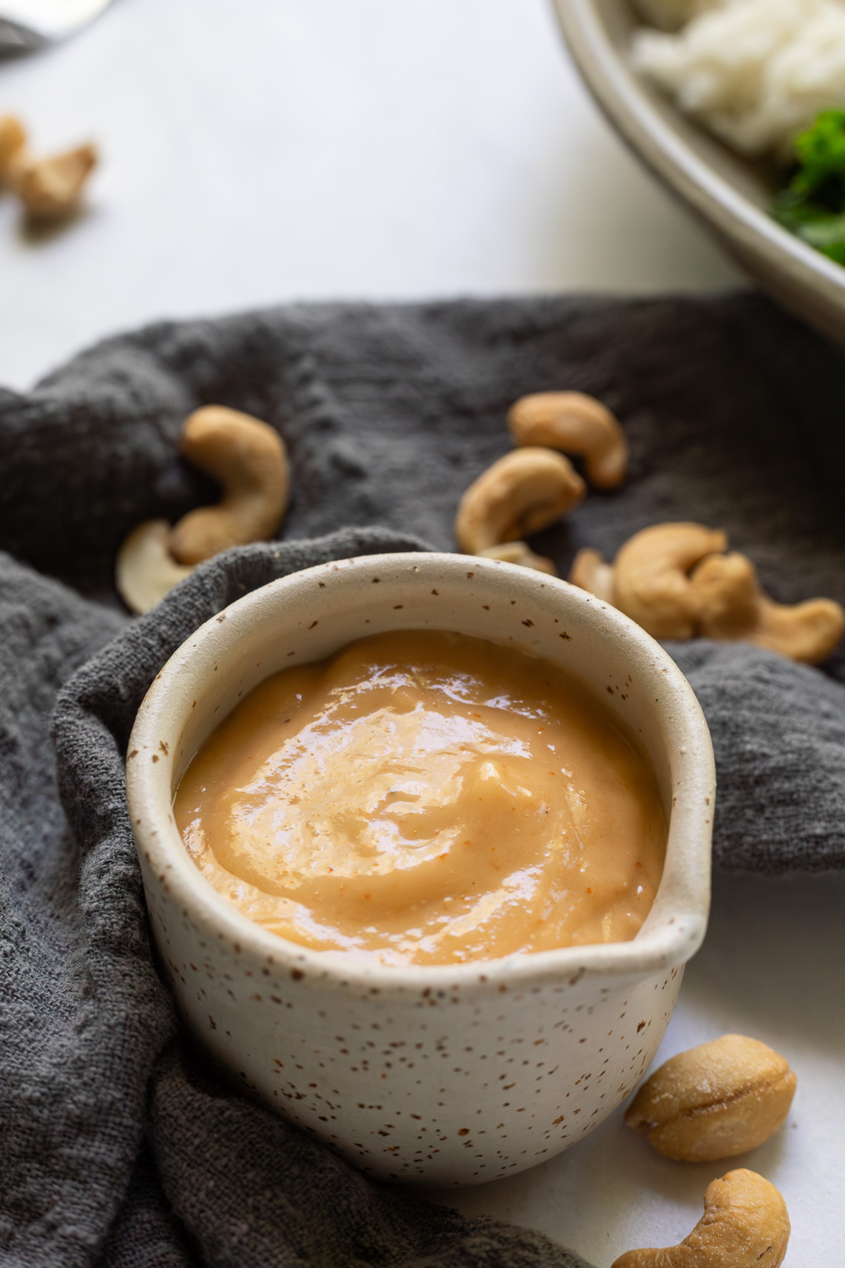 Creamy cashew dressing in a small pouring cup.