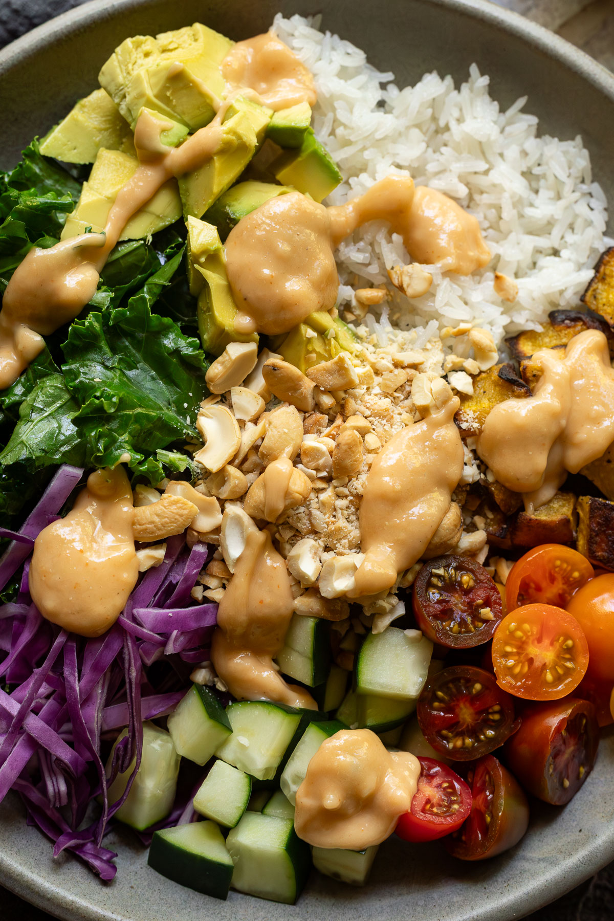 Side view of a cashew rice bowl with dressing on it.