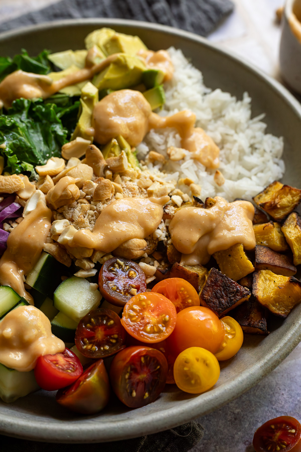 Side view of a cashew rice bowl with dressing on it.