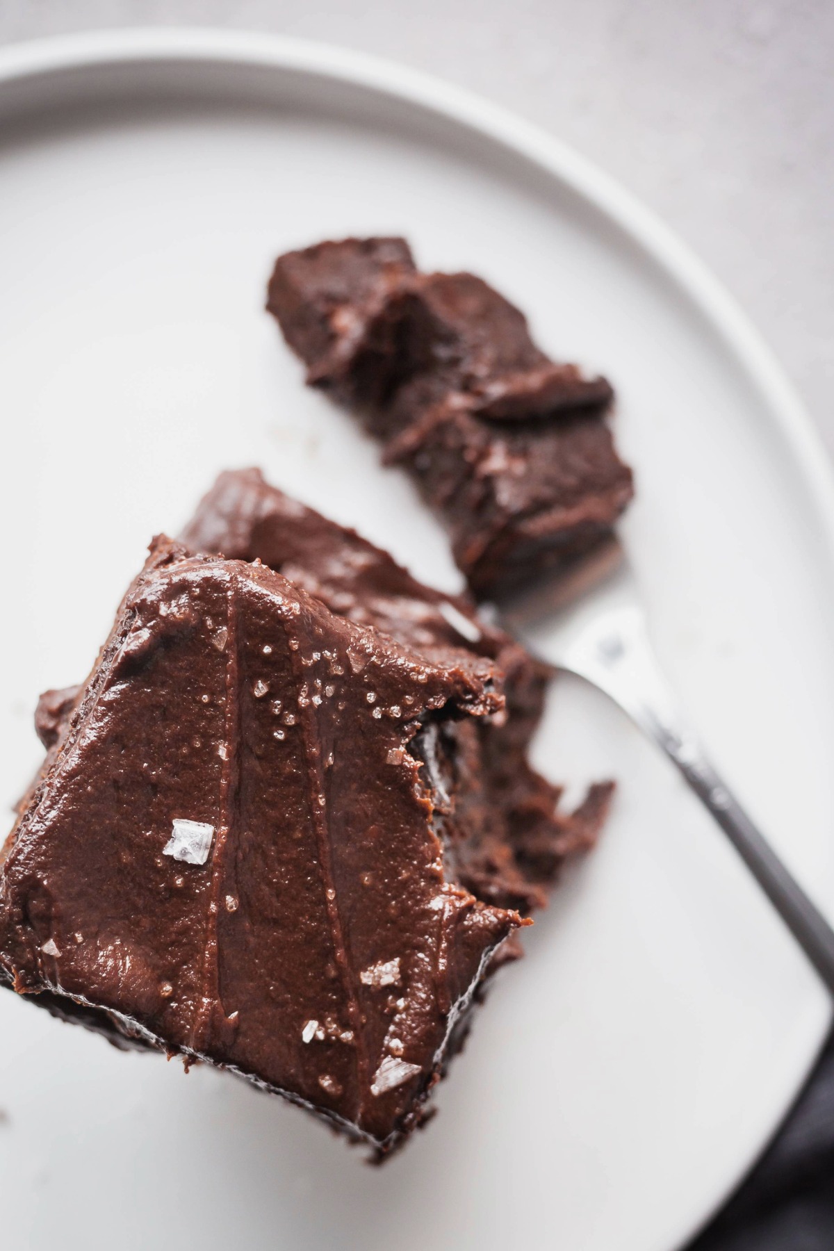 A stack of sweet potato brownies on a plate with a fork taking a bite out of them.