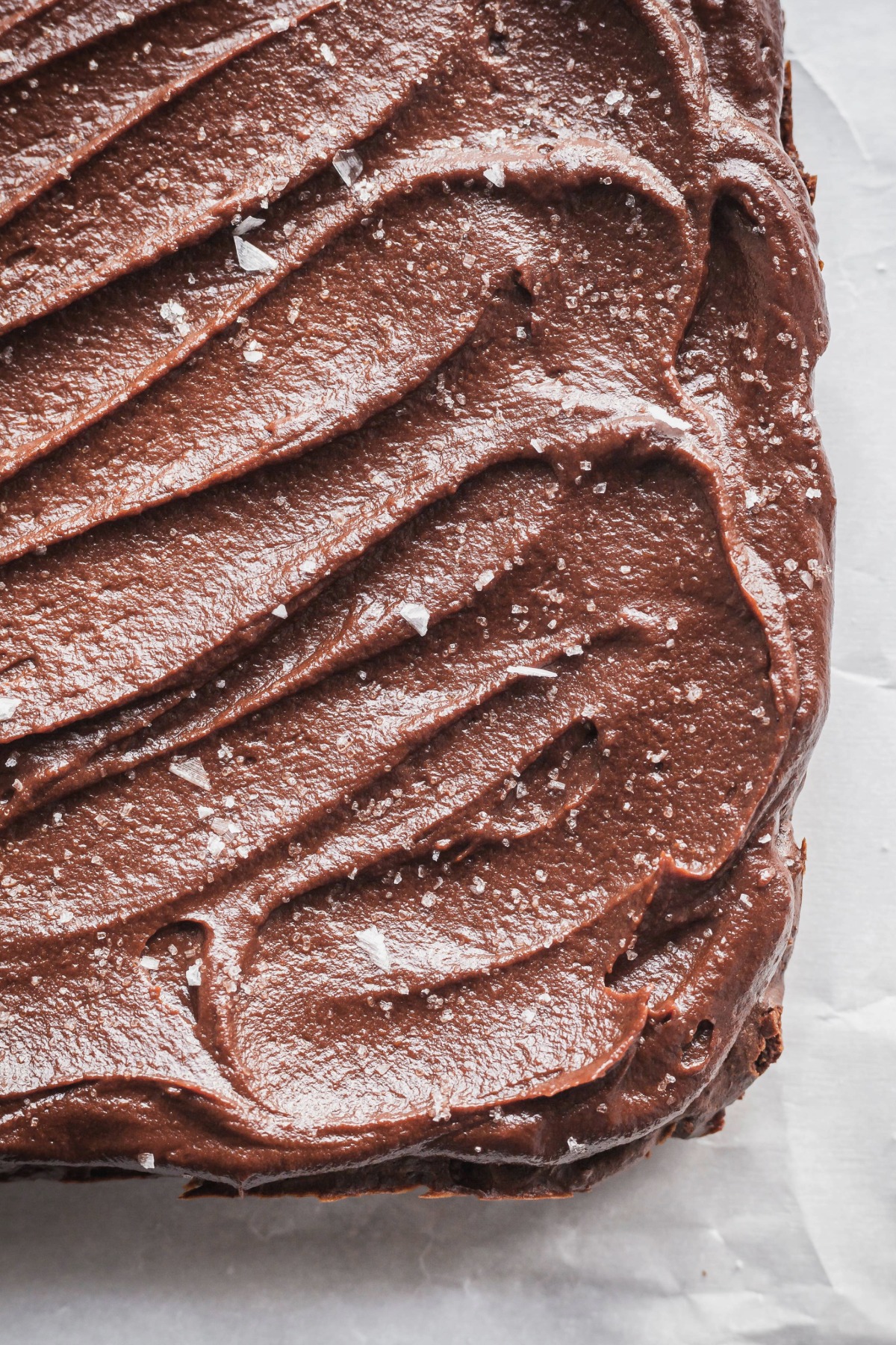 Frosting topped with flaky salt on sweet potato brownies before they have been cut.