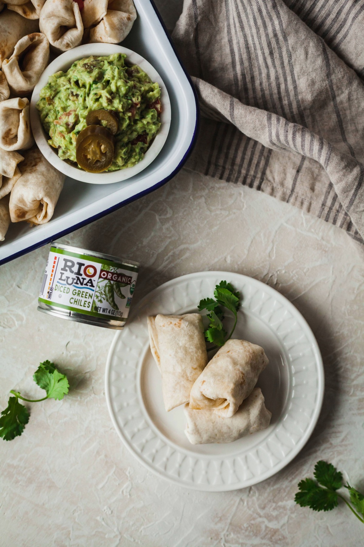 Two burrito bites on a plate next to a can of Rio Luna diced green chilies.