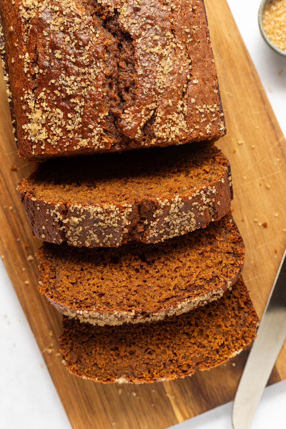Overhead shot of sliced gingerbread loaf on a cutting board with a knife next to it.