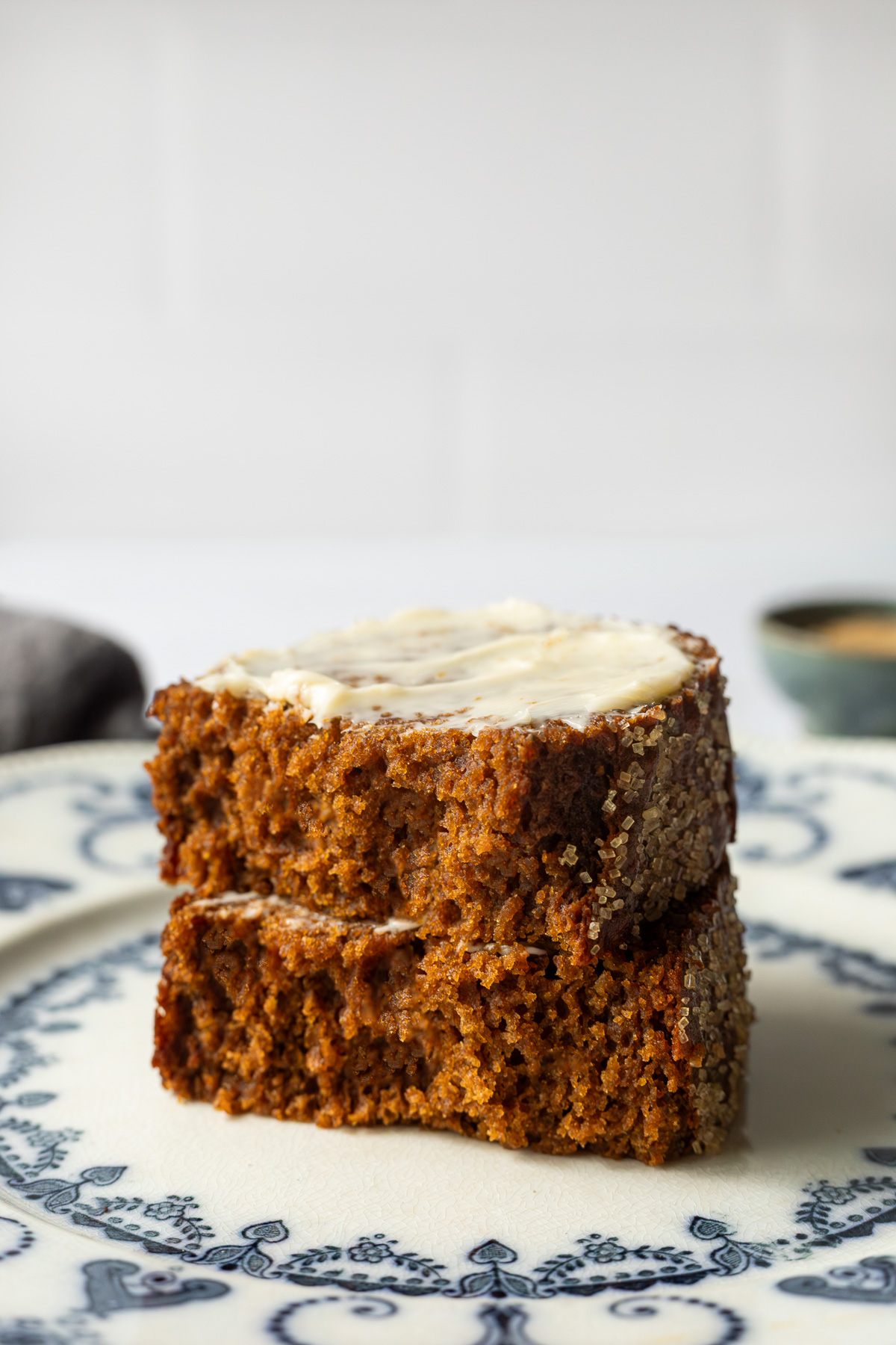 A slice of pumpkin gingerbread loaf topped with butter cut in half on a plate.