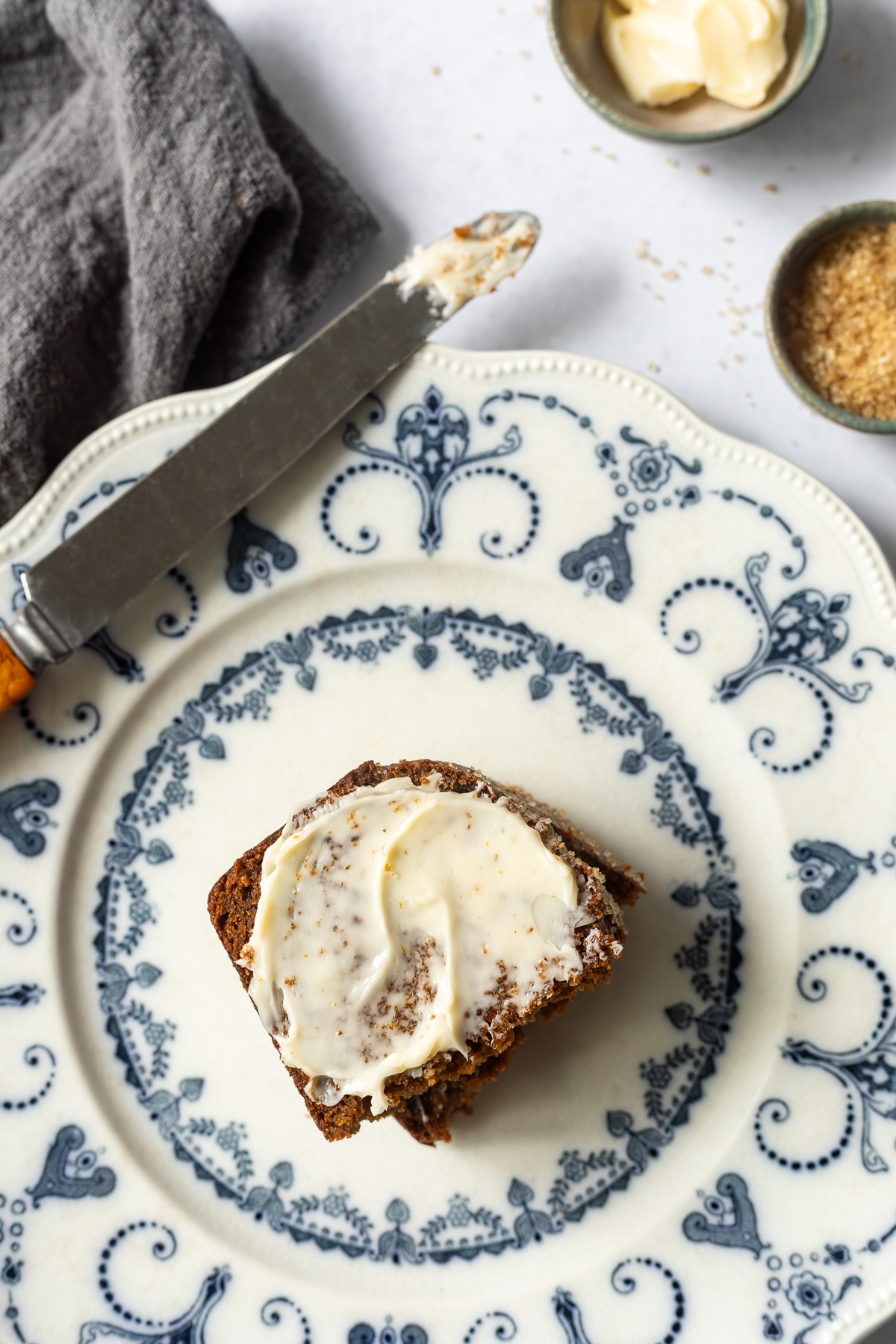 A slice of pumpkin gingerbread loaf topped with butter cut in half on a plate.