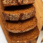 Overhead shot of sliced gingerbread loaf on a cutting board with a knife next to it.