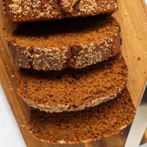 Overhead shot of sliced gingerbread loaf on a cutting board with a knife next to it.