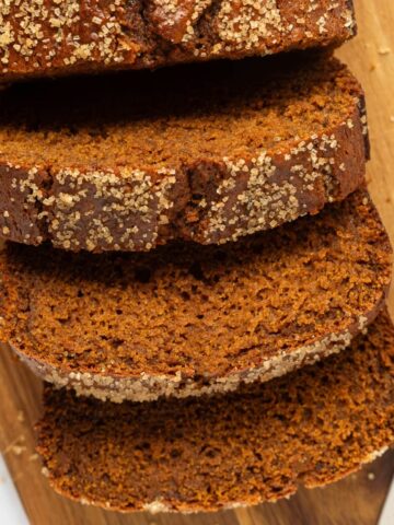 Overhead shot of sliced gingerbread loaf on a cutting board with a knife next to it.