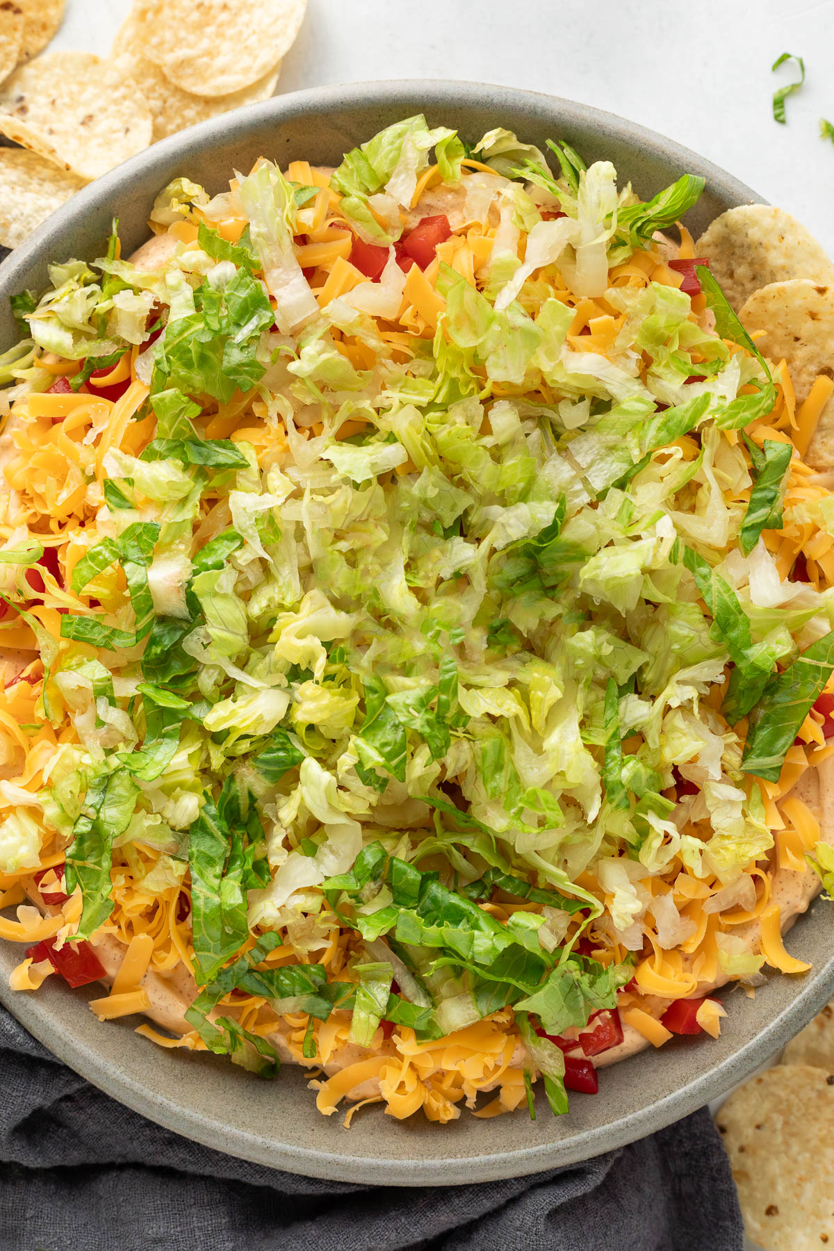 A bowl of taco dip with a chip sticking out of it.