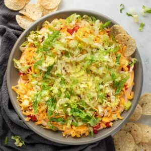 A bowl of taco dip with a chip sticking out of it.