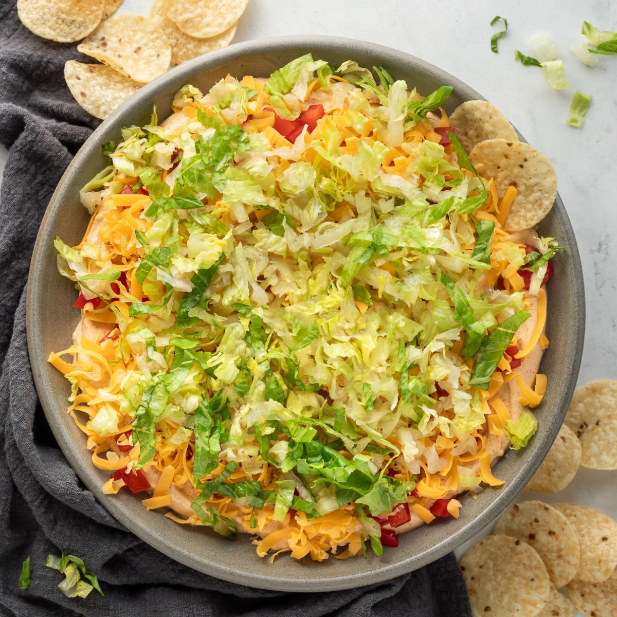 A bowl of taco dip with a chip sticking out of it.
