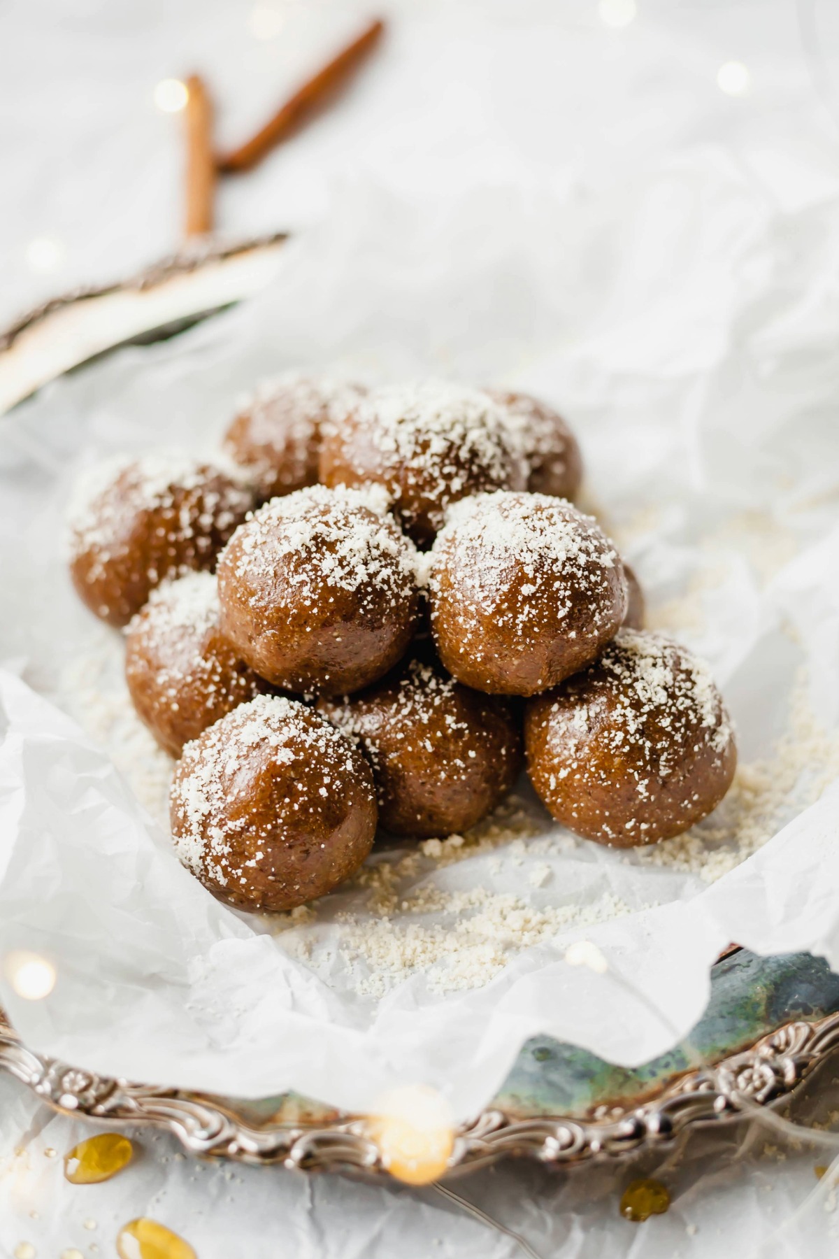 A pile of gingerbread energy balls on a tray with parchment paper on top. 