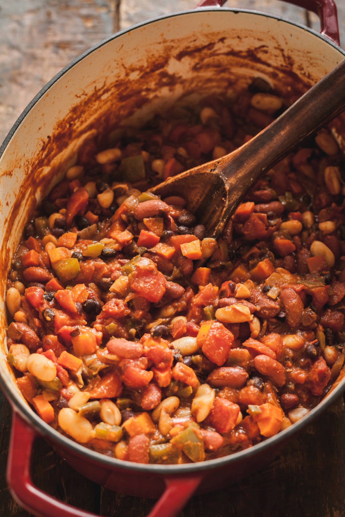 A pot of vegetarian chili with a wooden spoon sticking out of it.