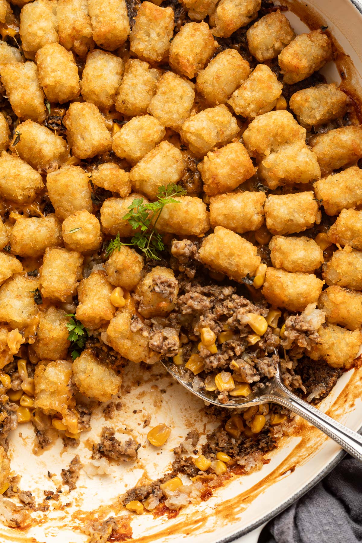 A spoon scooping into tater tot casserole.