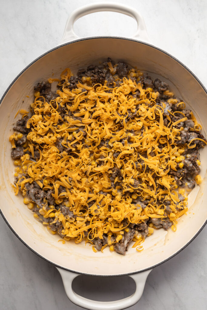 Meatless crumble, corn, cheese, and gravy in a braiser.