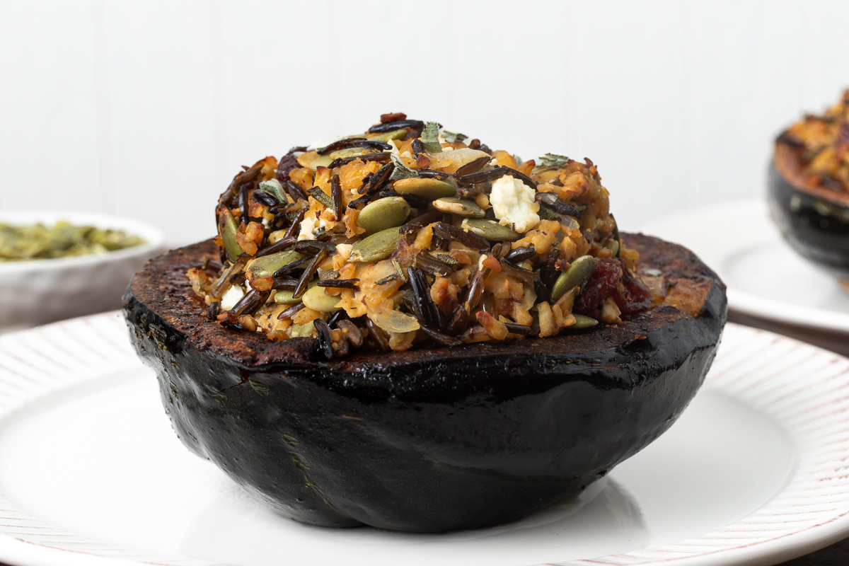 Side view of a stuffed acorn squash on a plate.