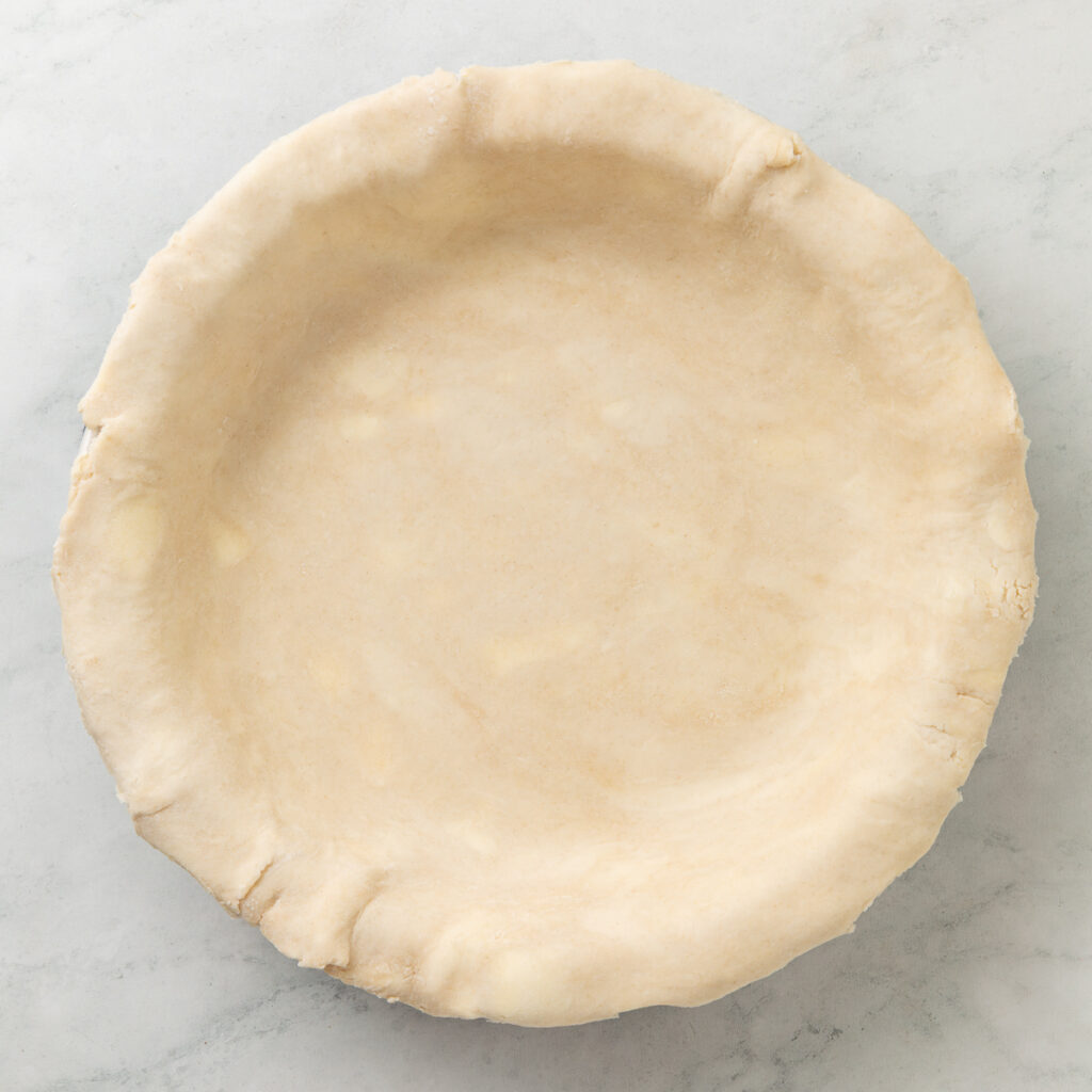 all butter pie crust in the baking dish after trimming the edges.
