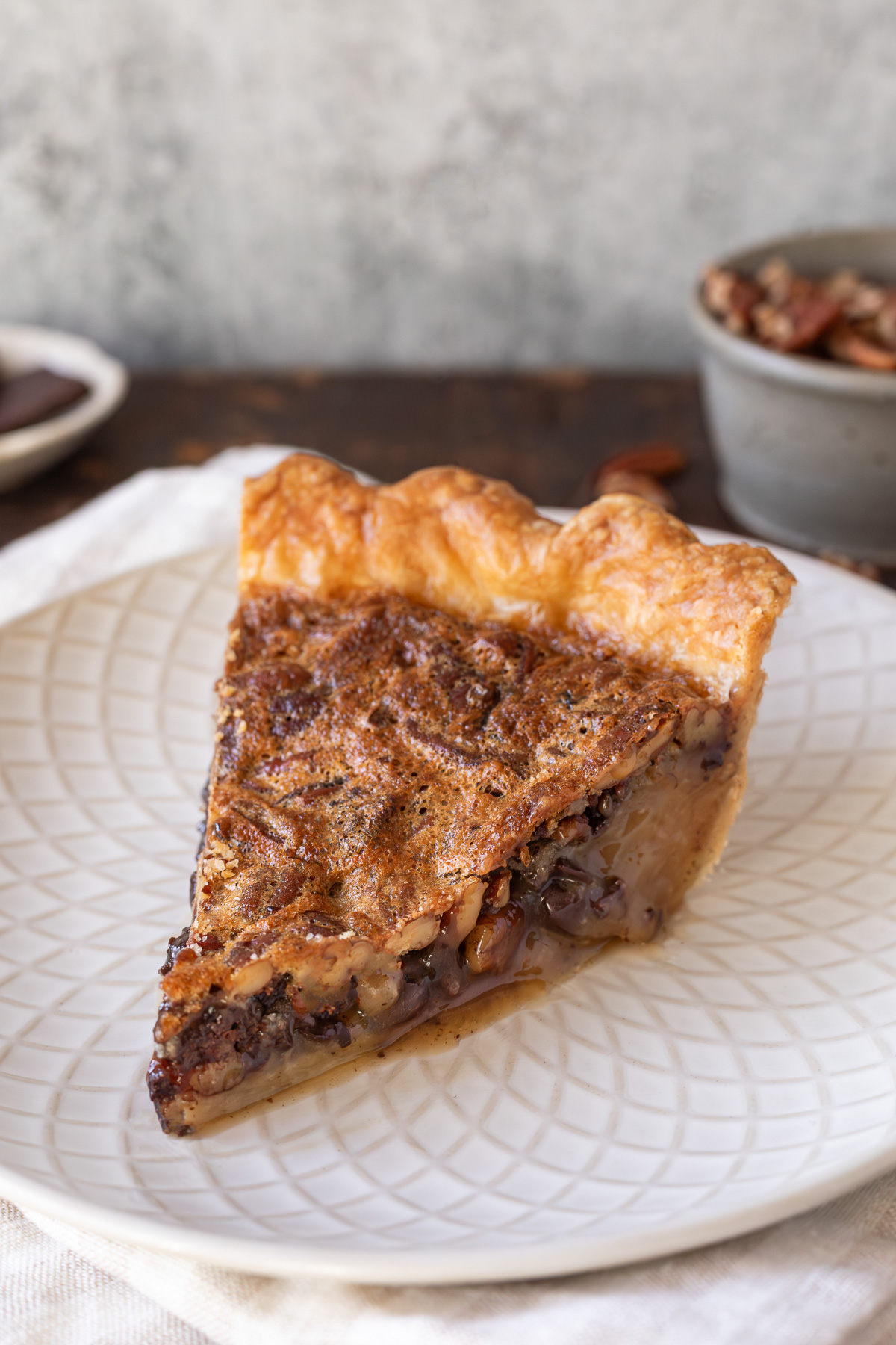 a slice of chocolate bourbon pecan pie on a small plate.
