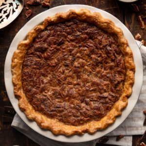 chocolate bourbon pecan pie on a wood table with a white striped napkin.