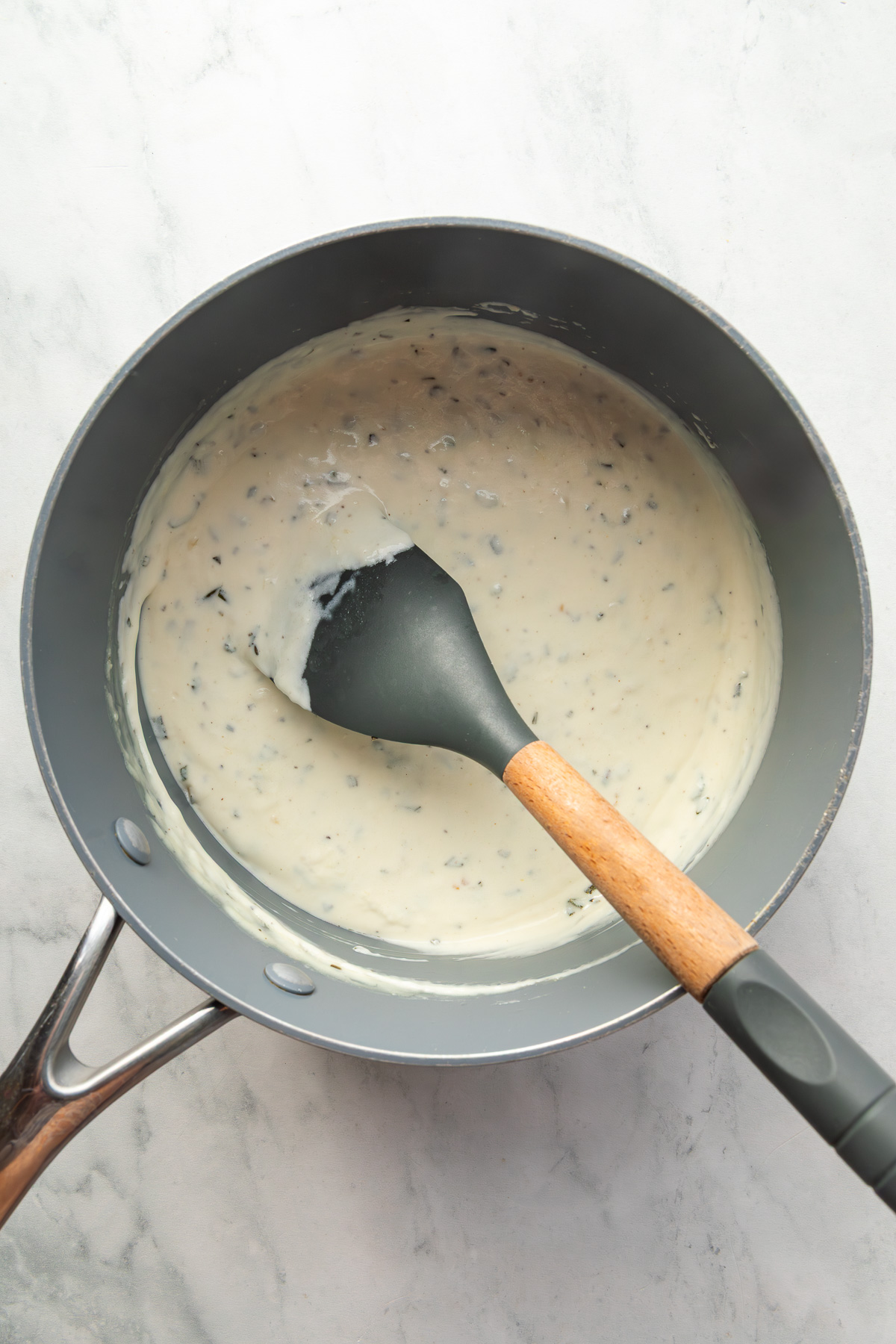 Cream sauce in a small pot with a spatula in it.