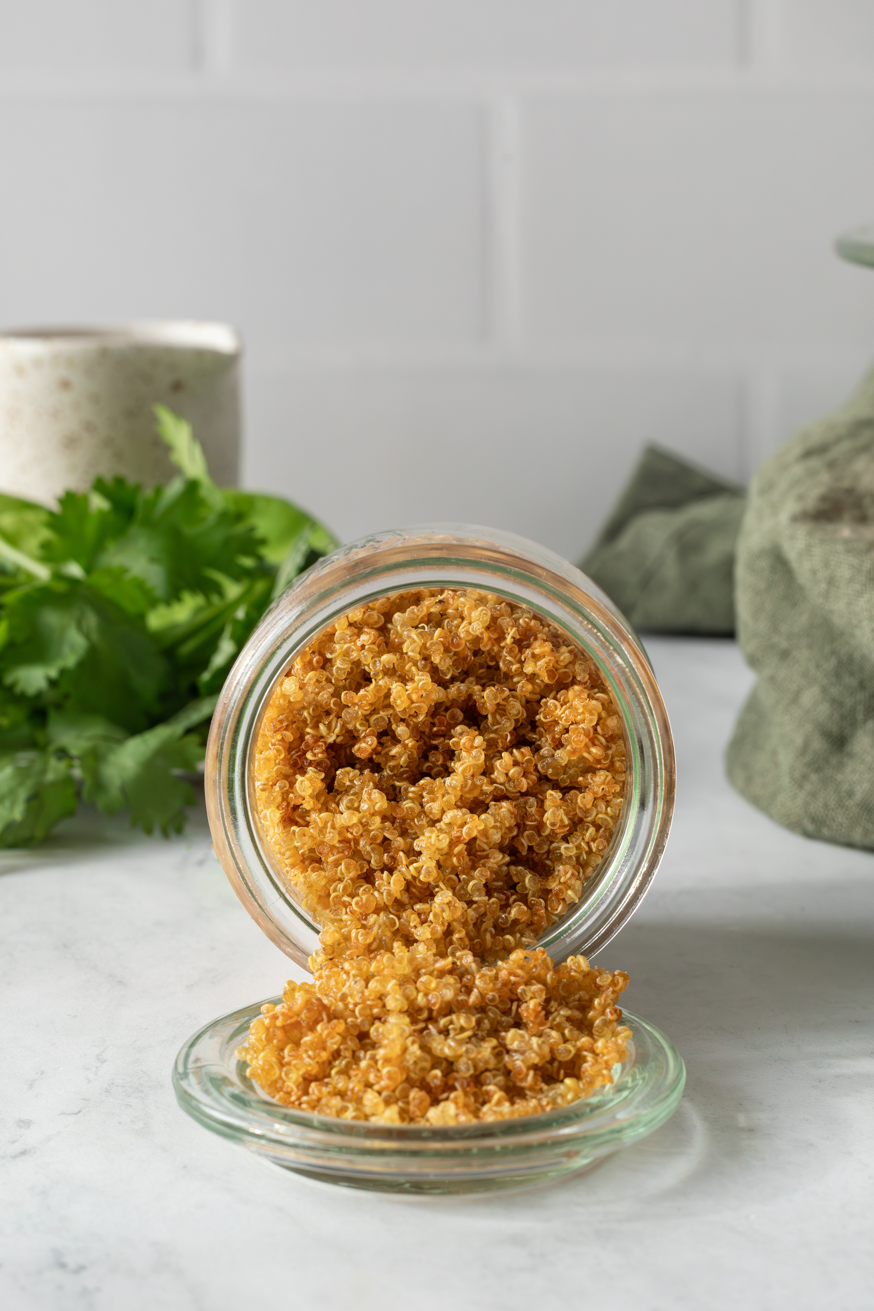 Crispy quinoa in a small jar with some of it spilling out on to the lid.