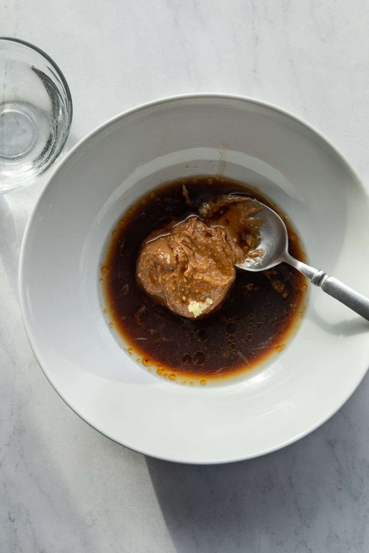 Ingredients for peanut dressing in a bowl with a spoon before it's mixed.