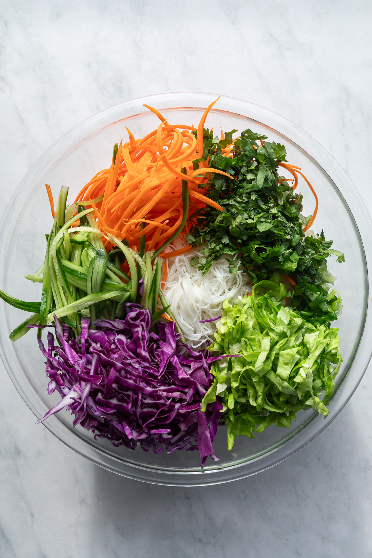 Ingredients to make a spring roll salad sectioned in a large mixing bowl.