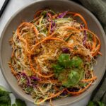 Ingredients to make a spring roll salad sectioned in a large mixing bowl.