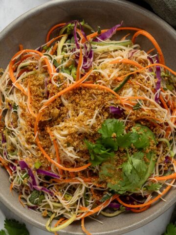 Ingredients to make a spring roll salad sectioned in a large mixing bowl.