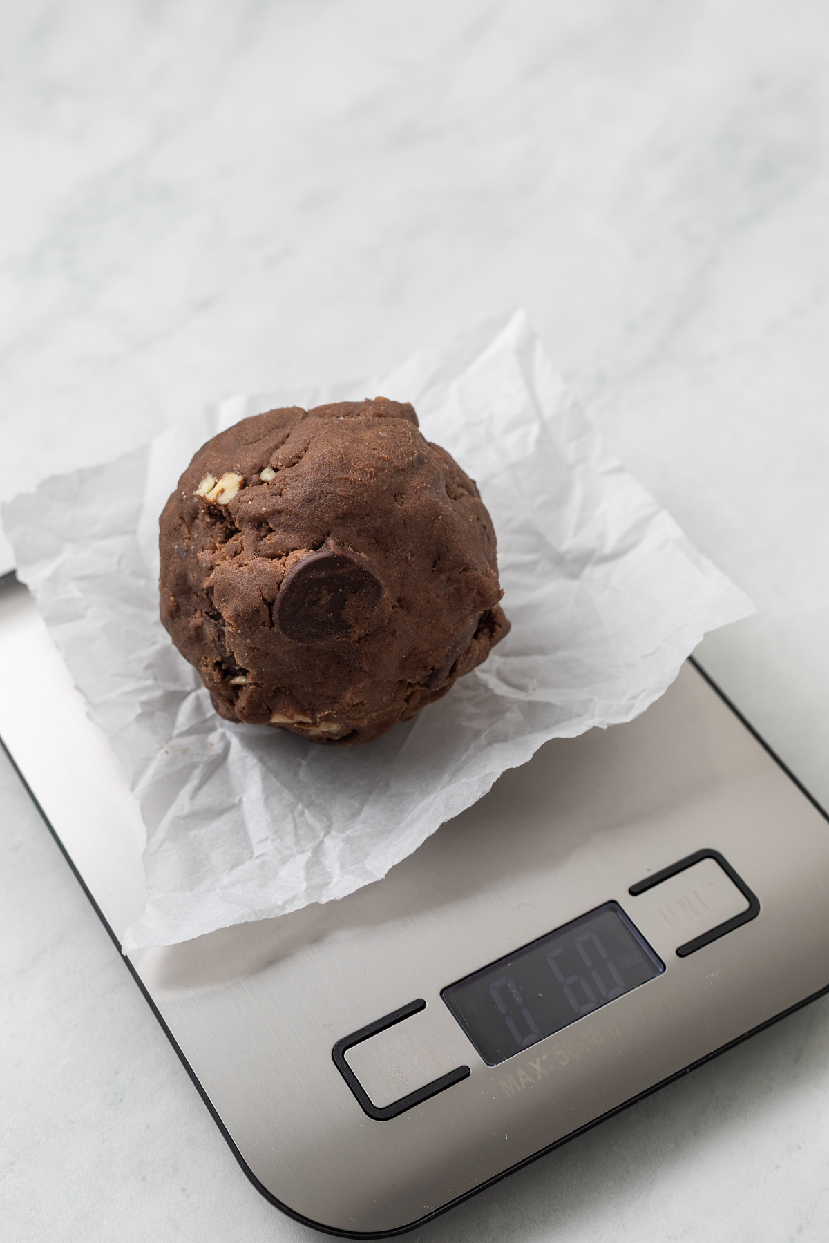 A ball of double chocolate chip cookie dough on a kitchen scale.