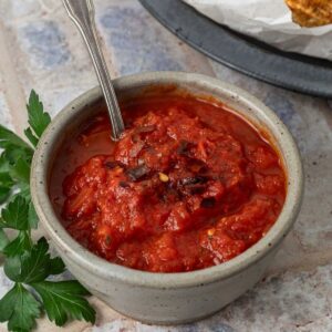 A small bowl of marinara dipping sauce with a spoon in it.