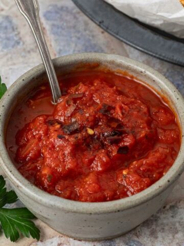 A small bowl of marinara dipping sauce with a spoon in it.
