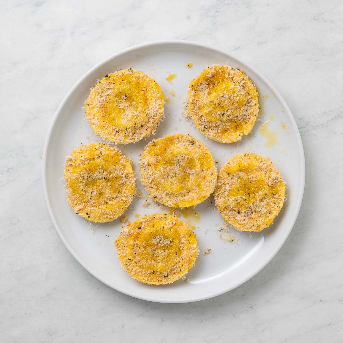 Cheese ravioli on a plate coated in breadcrumbs.