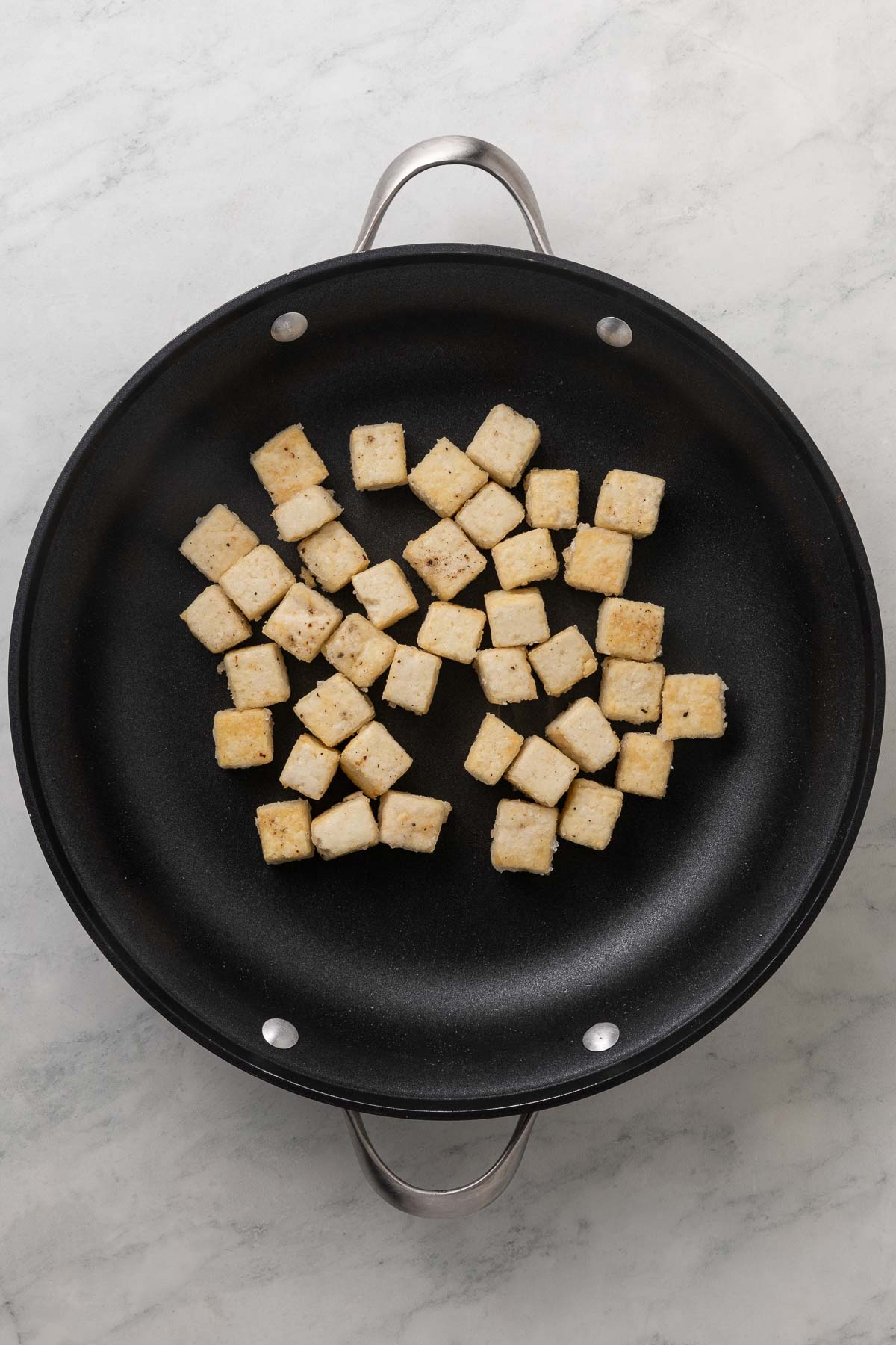 Tofu crisping in a pan.