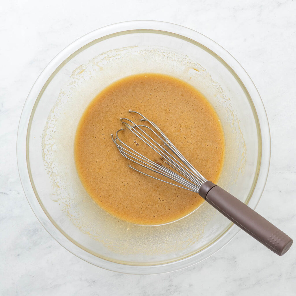 A bowl filled with brownie batter with a whisk in it.